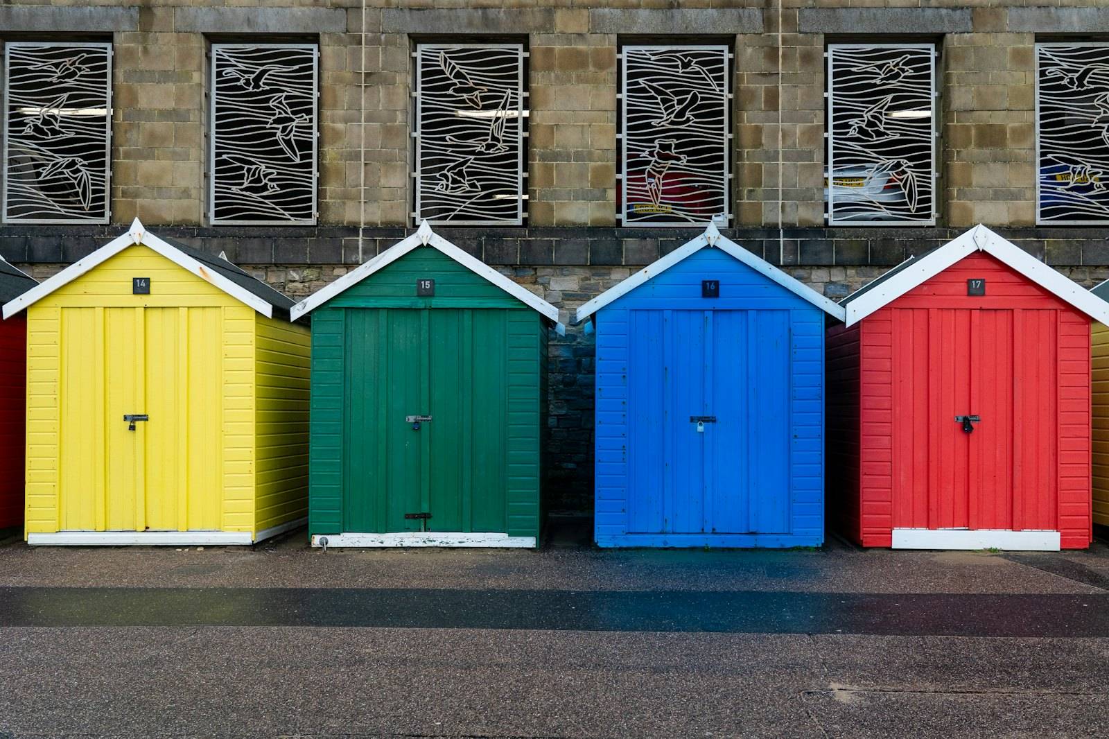 Yellow, green, blue and red beach hut doors in a row