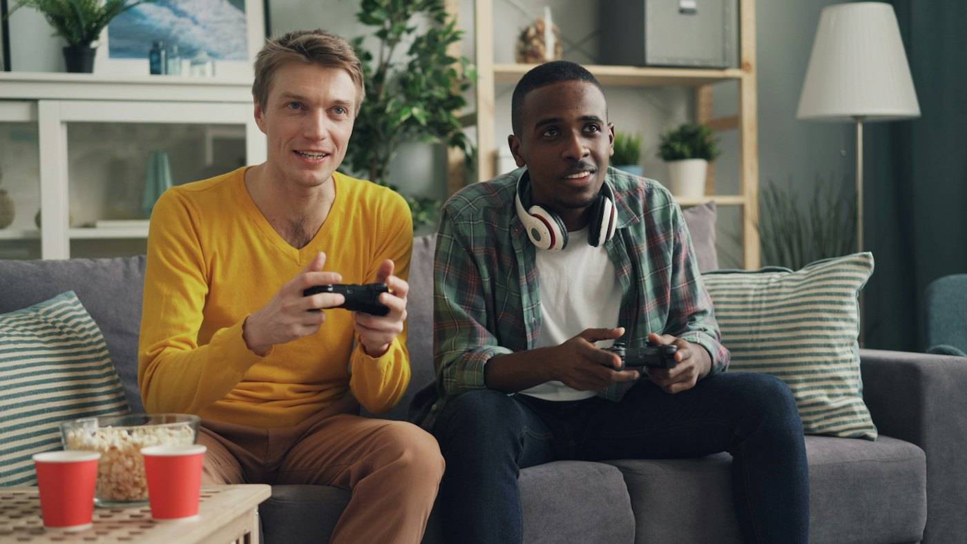 Two friends on a sofa playing a video game